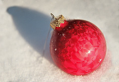 Red holiday ornament in the snow.